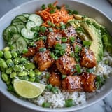 Vibrant baked salmon rice bowl with tender salmon cubes, fluffy rice, crisp cucumber, and creamy avocado, drizzled with spicy sriracha mayo.  