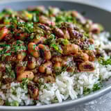 A vibrant vegetarian Hoppin John with black-eyed peas, bell peppers, and celery, served over fluffy rice and garnished with fresh parsley.