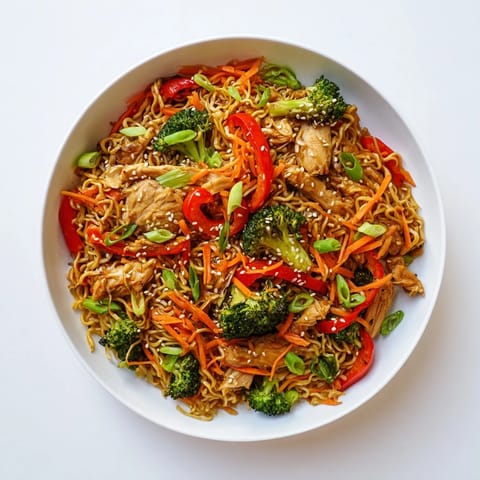 Steam rises from a wok filled with Spicy Ramen Stir-Fry, where bright vegetables and chicken mix with noodles, ready for a quick weeknight dinner.