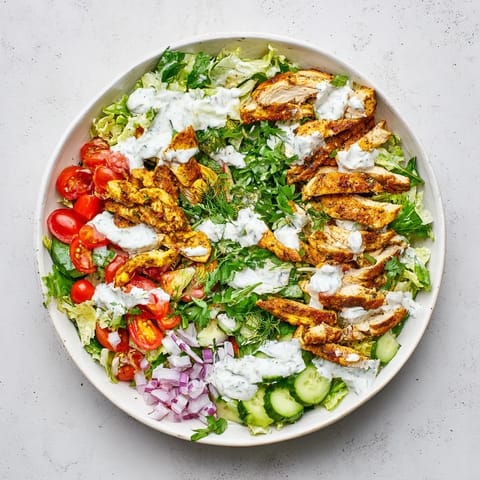 Tender golden-brown chicken shawarma slices top fresh greens, diced cucumbers, and halved cherry tomatoes in this colorful, satisfying salad bowl.  