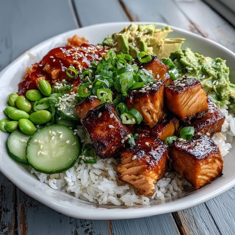 A spicy sriracha mayo drizzle garnishes this fresh Salmon Rice Bowl with avocado, green onions, and sesame seeds for a complete meal.