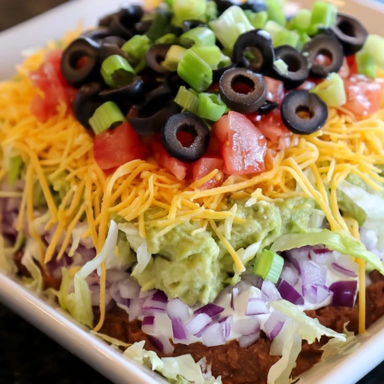 This seven-layer dip features shredded cheese and fresh toppings, perfect for sharing and parties.