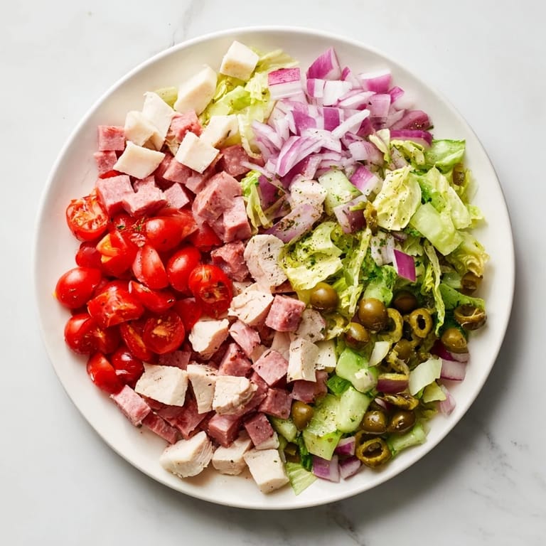 A hearty, gluten-free Italian Deli Chopped Chicken Salad served in a rustic bowl, garnished with pepperoncini, cherry tomatoes, and fresh herbs.  