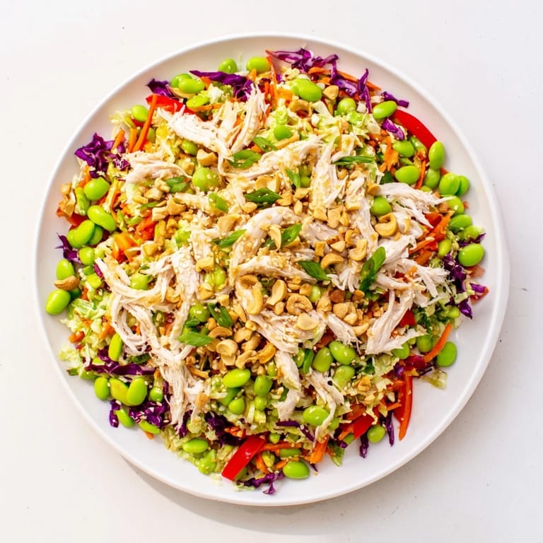 Vibrant Edamame Crunch Chicken Salad topped with toasted sesame seeds and cashews, served as a refreshing protein-packed lunch.