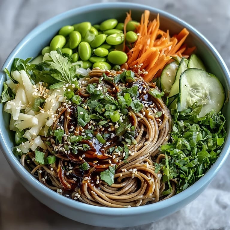 Fresh Soba Noodle Bowl tossed with sesame dressing, edamame, and vibrant veggies, garnished with green onions.